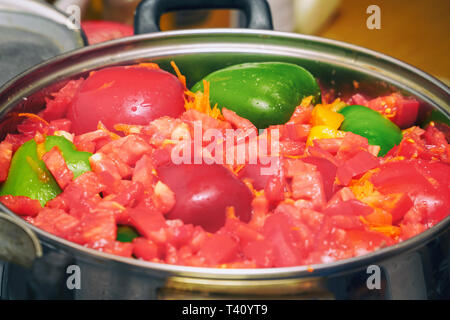Tagliato a pezzi ortaggi - peperoni, pomodori, ecc. - In metallo lucido pan. Messa a fuoco selettiva Foto Stock