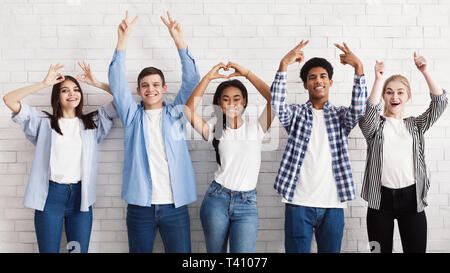 Teen amici gesti con le mani sul muro bianco Foto Stock