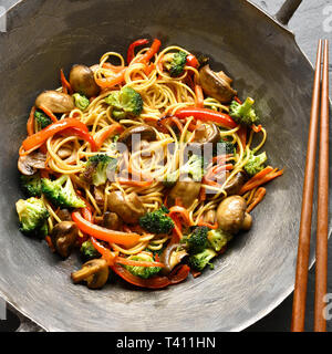 Close up di mescolare verdure fritte con tagliatelle in padella wok. Vista superiore, laici piatta Foto Stock