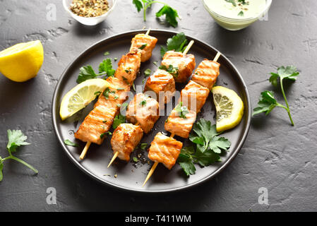 Barbecue spiedini di salmone su nero tavolo di pietra. Salmone alla griglia kebab. Foto Stock