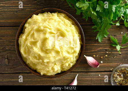 Purè di patate nella ciotola sul tavolo di legno. Vista superiore, laici piatta Foto Stock