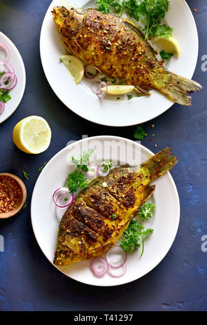 Pesce arrosto su piastra su pietra blu sullo sfondo. Frutti di mare. Vista superiore, laici piatta Foto Stock