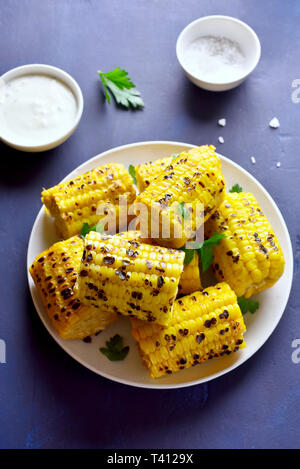Grigliata di mais dolce sulla piastra su pietra blu sullo sfondo. Vegetariano vegano cibo. Gustosa merenda Foto Stock