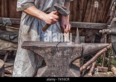 Fabbro medievale al lavoro con martello e l'incudine. Foto Stock