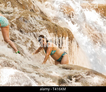 Una donna si arrampica in una cascata - Cascate del Fiume Dunn in Giamaica Foto Stock