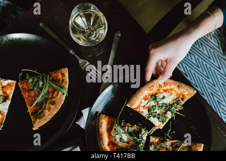 Donna seduta a tavola a mangiare la pizza Foto Stock