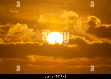 La mattina presto sole che splende attraverso le nuvole in colori drammatici Foto Stock