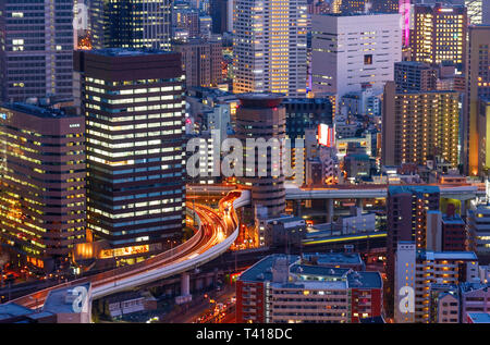 Vista aerea di una autostrada che attraversano un edificio per uffici nel quartiere Umeda durante il tramonto. Osaka, Giappone. Foto Stock