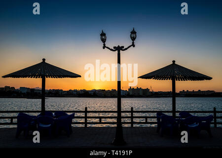 Silhouette di ombrelloni sopra il tavolo e sedie nel parco, Hurghada, Egitto Foto Stock