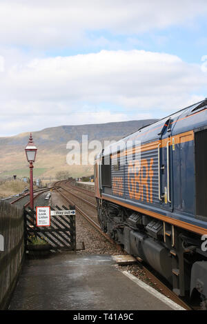 Classe 66 GBRf locomotiva diesel-elettriche trasporta un treno di pietra attraverso Ribblehead stazione da stabilirsi a Carlisle linea ferroviaria il 12 aprile 2019. Foto Stock