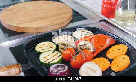 Un lavoro dello chef in cucina. Riscaldamento dei funghi e verdure in padella senza olio Foto Stock