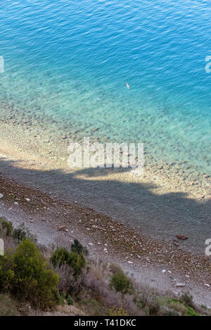 Bellissimo paesaggio marino con il blu del mare sullo sfondo e la spiaggia di ciottoli in primo piano, la luce solare e le ombre, paesaggio verticale Foto Stock