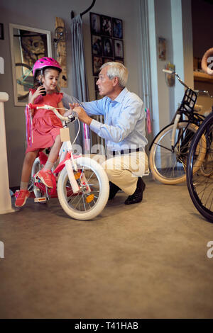 Felice nonni acquisto nuova bicicletta e caschi per bambina Foto Stock