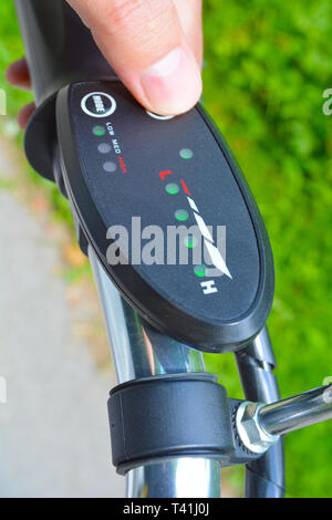 Girando sulla bicicletta elettrica E-bike o bicicletta. Premendo un pulsante sulla scheda di controllo o il controller per scegliere la velocità e il livello di potenza. Non filtrato con natura Foto Stock