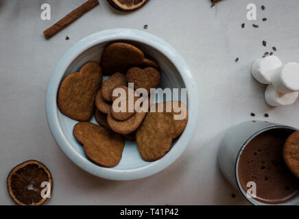 A forma di cuore biscotti in una ciotola blu con decorazioni Foto Stock