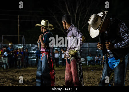 Latin bull riders getting chiamato fuori prima di equitazione in rodeo guatemalteca Foto Stock