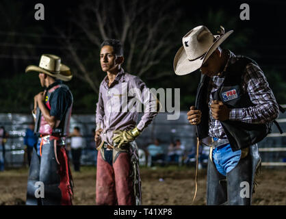 Latin bull riders getting chiamato fuori prima di equitazione in rodeo guatemalteca Foto Stock