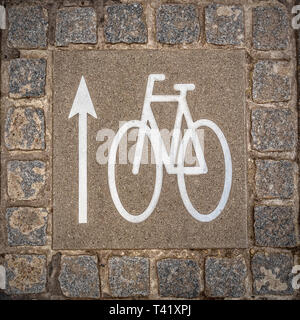 Una bicicletta lane segno sul terreno che indica la direzione di marcia. Foto Stock