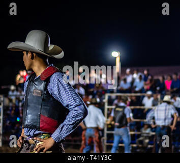 Latin bull riders getting chiamato fuori prima di equitazione in rodeo guatemalteca Foto Stock