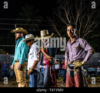Latin bull riders getting chiamato fuori prima di equitazione in rodeo guatemalteca Foto Stock
