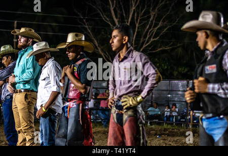 Latin bull riders getting chiamato fuori prima di equitazione in rodeo guatemalteca Foto Stock