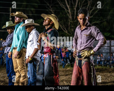 Latin bull riders getting chiamato fuori prima di equitazione in rodeo guatemalteca Foto Stock