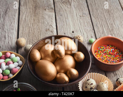 Uova pasquali dipinte in colore oro nella ciotola di legno Foto Stock