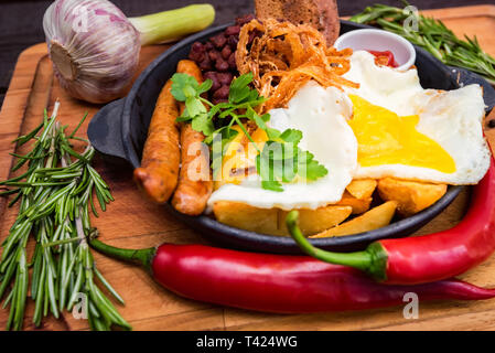 Pasto con uova fritte, salsicce, fagioli, anelli di cipolla, peperoncino e salsa Foto Stock