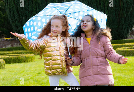 Il ricovero di bambini al di sotto di un ombrello Foto Stock