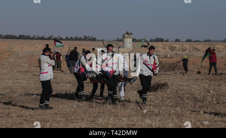 La striscia di Gaza, la Palestina. Xii Apr, 2019. Aprile 12, 2019 - Gaza, Palestina, Palestina - palestinesi paramedici sono visto che trasporta un manifestante ferito durante la dimostrazione vicino al confine con Israele, a est di Khan Yunis nel sud della striscia di Gaza..un ragazzo palestinese è stato ucciso dall'esercito israeliano durante il rinnovato scontri di frontiera Gaza, il ministero della salute nella enclave palestinese ha detto un portavoce del ministero Maysara detto Abu Shaloof, 15, era "hot nello stomaco dall'(israeliana) occupazione a est di Jabalia'', facendo riferimento ad un sito di dimostrazione nel nord della Striscia di Gaza. Credito: ZUMA Press, Inc./ Foto Stock