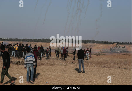 La striscia di Gaza, la Palestina. Xii Apr, 2019. Aprile 12, 2019 - Gaza, Palestina, Palestina - i palestinesi sono visti tenendo il coperchio nel mezzo di gas lacrimogeni sparati dalle forze di Israele durante la dimostrazione vicino al confine con Israele, a est di Khan Yunis nel sud della striscia di Gaza..un ragazzo palestinese è stato ucciso dall'esercito israeliano durante il rinnovato scontri di frontiera Gaza, il ministero della salute nella enclave palestinese ha detto un portavoce del ministero Maysara detto Abu Shaloof, 15, era "hot nello stomaco dall'(israeliana) occupazione a est di Jabalia'', facendo riferimento ad un sito di dimostrazione nel nord della Striscia di Gaza. Credito: Z Foto Stock