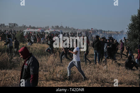 La striscia di Gaza, la Palestina. Xii Apr, 2019. Aprile 12, 2019 - Gaza, Palestina, Palestina - i palestinesi sono visti tenendo il coperchio nel mezzo di gas lacrimogeni sparati dalle forze di Israele durante la dimostrazione vicino al confine con Israele, a est di Khan Yunis nel sud della striscia di Gaza..un ragazzo palestinese è stato ucciso dall'esercito israeliano durante il rinnovato scontri di frontiera Gaza, il ministero della salute nella enclave palestinese ha detto un portavoce del ministero Maysara detto Abu Shaloof, 15, era "hot nello stomaco dall'(israeliana) occupazione a est di Jabalia'', facendo riferimento ad un sito di dimostrazione nel nord della Striscia di Gaza. Credito: Z Foto Stock