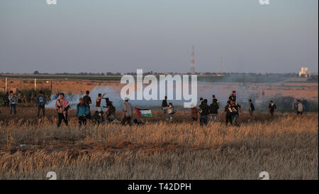 La striscia di Gaza, la Palestina. Xii Apr, 2019. Aprile 12, 2019 - Gaza, Palestina, Palestina - i palestinesi sono visti tenendo il coperchio nel mezzo di gas lacrimogeni sparati dalle forze di Israele durante la dimostrazione vicino al confine con Israele, a est di Khan Yunis nel sud della striscia di Gaza..un ragazzo palestinese è stato ucciso dall'esercito israeliano durante il rinnovato scontri di frontiera Gaza, il ministero della salute nella enclave palestinese ha detto un portavoce del ministero Maysara detto Abu Shaloof, 15, era "hot nello stomaco dall'(israeliana) occupazione a est di Jabalia'', facendo riferimento ad un sito di dimostrazione nel nord della Striscia di Gaza. Credito: Z Foto Stock