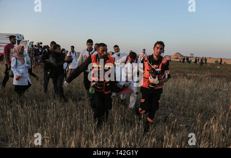 I paramedici palestinesi sono visto che trasporta un manifestante ferito durante la dimostrazione vicino al confine con Israele, a est di Khan Yunis nel sud della striscia di Gaza. Un ragazzo palestinese è stato ucciso dall'esercito israeliano durante il rinnovato scontri di frontiera Gaza, il ministero della salute nella enclave palestinese ha detto un portavoce del ministero Maysara detto Abu Shaloof, 15, era "hot nello stomaco dall'(israeliana) occupazione a est di Jabalia,' in riferimento ad un sito di dimostrazione nel nord della Striscia di Gaza. Foto Stock