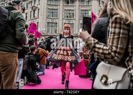 Aprile 12, 2019 - Londra, Londo, Regno Unito - una donna attivista visto la presentazione durante l'evento..L'estinzione della ribellione di moda gruppo di azione è andato a Oxford Circus a un fermo dall'allestimento di un creativo e simbolico chiamato passerella moda: Circo di eccesso. L obiettivo è quello di raccogliere l'allarme circa il ruolo del consumo di moda gioca in alimentando il clima e l'emergenza ecologica. Il settore della moda è impostato a consumare un quarto del mondo€™s bilancio di carbonio dal 2050 nella produzione di capi di abbigliamento. (Credito Immagine: © Brais G. Rouco/SOPA immagini via ZUMA filo) Foto Stock