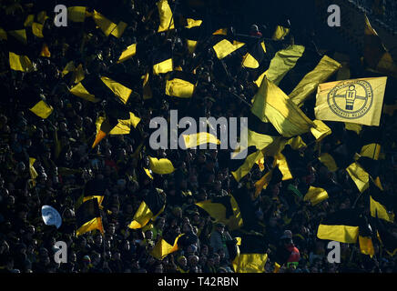 Dortmund, Germania. Xiii Apr, 2019. Calcio: Bundesliga, Borussia Dortmund - FSV Mainz 05, XXIX Giornata al Signal Iduna Park. Gli appassionati di Dortmund wave loro bandiere prima della partita. Credito: Ina Fassbender/dpa - NOTA IMPORTANTE: In conformità con i requisiti del DFL Deutsche Fußball Liga o la DFB Deutscher Fußball-Bund, è vietato utilizzare o hanno utilizzato fotografie scattate allo stadio e/o la partita in forma di sequenza di immagini e/o video-come sequenze di foto./dpa/Alamy Live News Foto Stock