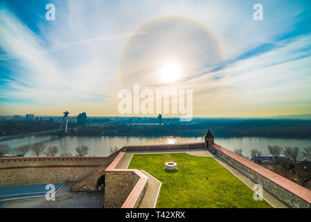 Alone solare oltre il Fiume Danubio e il castello medievale di Bratislava, Slovacchia Foto Stock