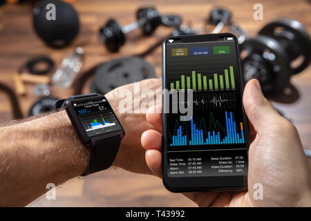 Close-up di mano d'uomo con Smartwatch e cellulare di monitoraggio della frequenza cardiaca in palestra Foto Stock