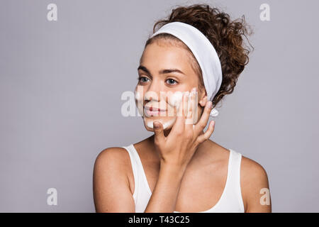 Ritratto di una giovane donna faccia pulizia in uno studio, la bellezza e la cura della pelle. Foto Stock