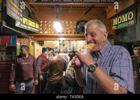 Ritratto orizzontale di un turista occidentale di mangiare streetfood in Kolkata aka Calcutta, India. Foto Stock