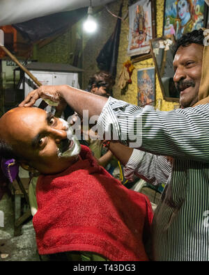 Ritratto verticale di un uomo avente una rasatura sul ciglio della strada in Kolkata aka Calcutta, India. Foto Stock