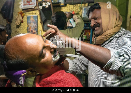Ritratto orizzontale di un barbiere al lavoro in Kolkata aka Calcutta, India. Foto Stock