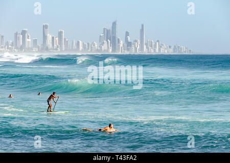 La gente sulla spiaggia, per nuotare e fare surf, a Burleigh capi, Gold Coast, Queensland, Australia. Surfers Paradise in distanza. Foto Stock