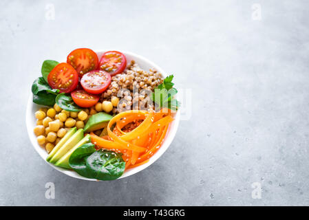 Ciotola di Buddha con insalata di grano saraceno, avocado, carote, pomodoro, spinaci, ceci su grigio. Vegetariano sana dieta vegana mangiare, super cibo. Vista superiore, copia Foto Stock
