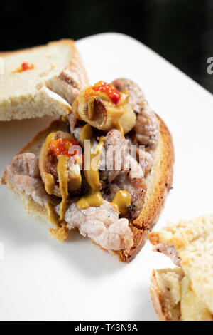 Famoso e tradizionale portoghese marinato bifana di maiale piccante snack a sandwich con senape piri piri e salsa di aglio a Lisbona cafe Foto Stock