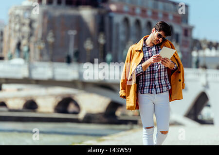 Moda uomo d affari utilizzando PC tablet whie andando dal Boardwalk Foto Stock