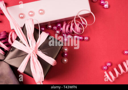 Serie di confezioni regalo con archi, perle e nastri su uno sfondo colorato Foto Stock