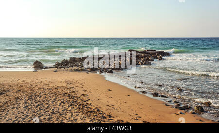 Spiaggia vuota con orme, alcune rocce in mare in serata alcuni istanti prima del tramonto. Lapta, la parte settentrionale di Cipro Foto Stock