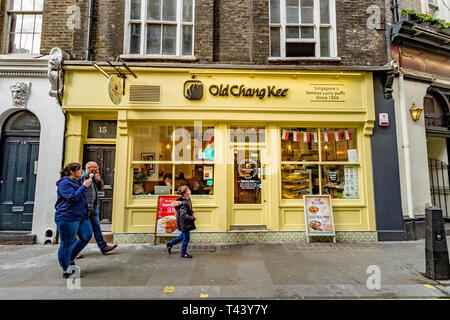 Una famiglia cammina attraverso Old Chang Kee, Londra, un ristorante specializzato nel Singapore curry puff, una versione piccante della pasta Cornish, Londra, Regno Unito Foto Stock