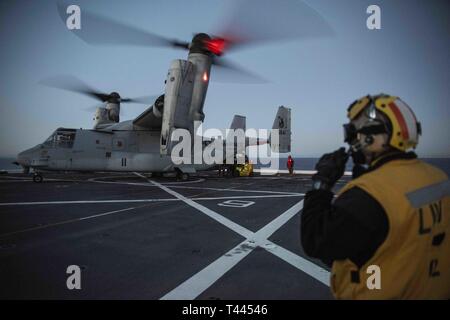 Oceano Pacifico (16 marzo 2019) - Aviazione di Boatswain Mate (manipolazione) 1a classe Pietro Obeng comunica con la torre di controllo durante le operazioni di volo con un MV-22B Osprey dal mezzo marino Tiltrotor Squadron 164 sul ponte di volo della USS New Orleans (LPD 18) durante l'esercizio pacifico Blitz 19. Pacific Blitz è uno scenario-driven esercizio congiunto che fornisce corsi di formazione pertinenti dalla replica di una realistica minaccia marittima ambiente concepito per stimolare e migliorare la capacità anfibie necessaria per una effettiva crisi globale risposta. Foto Stock